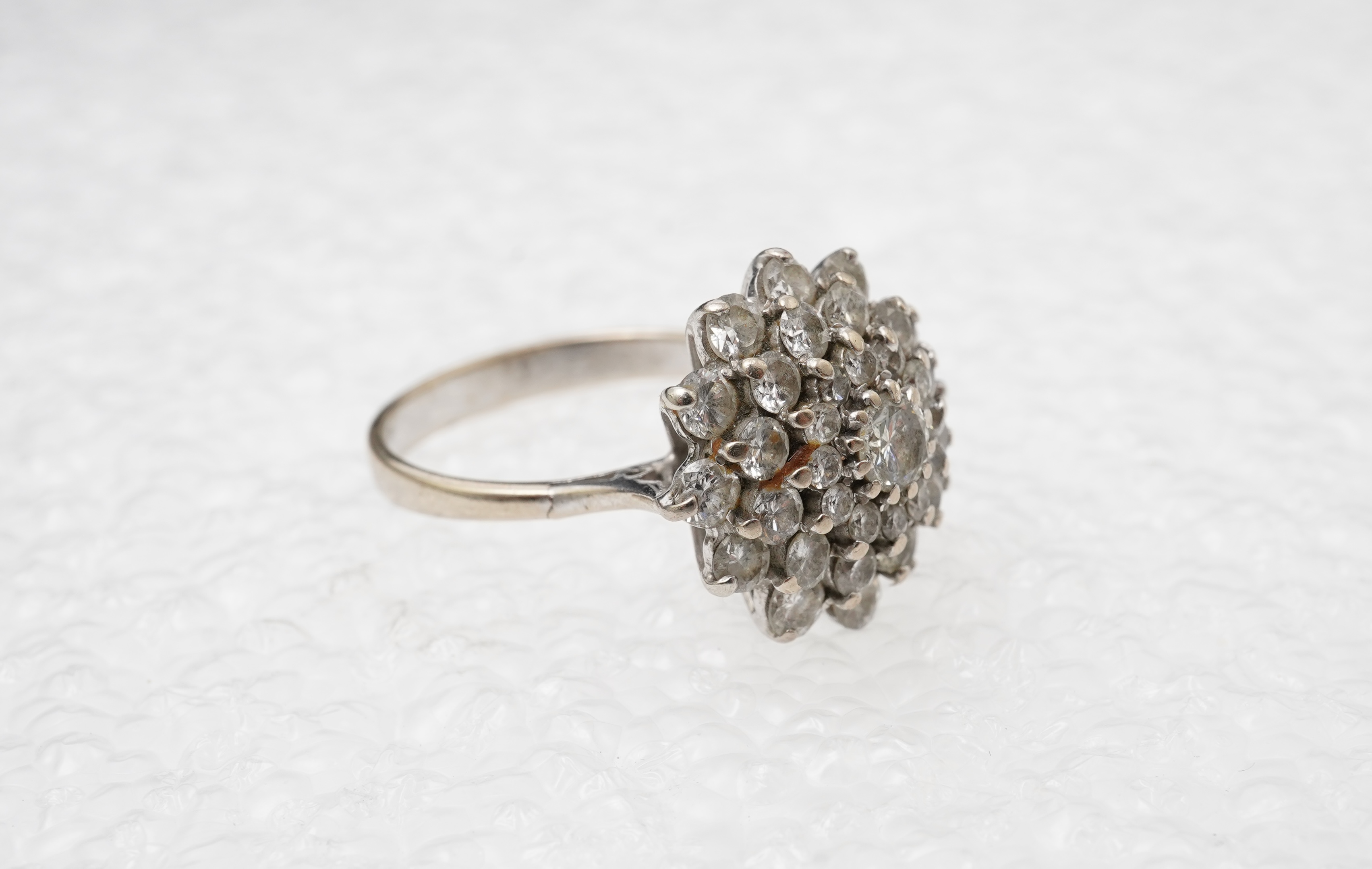 A white gold and diamond cluster ring, set with a concentric arrangement of brilliant-cut diamonds totalling approximately 1.50 carats, size M, gross weight approximately 5 grams